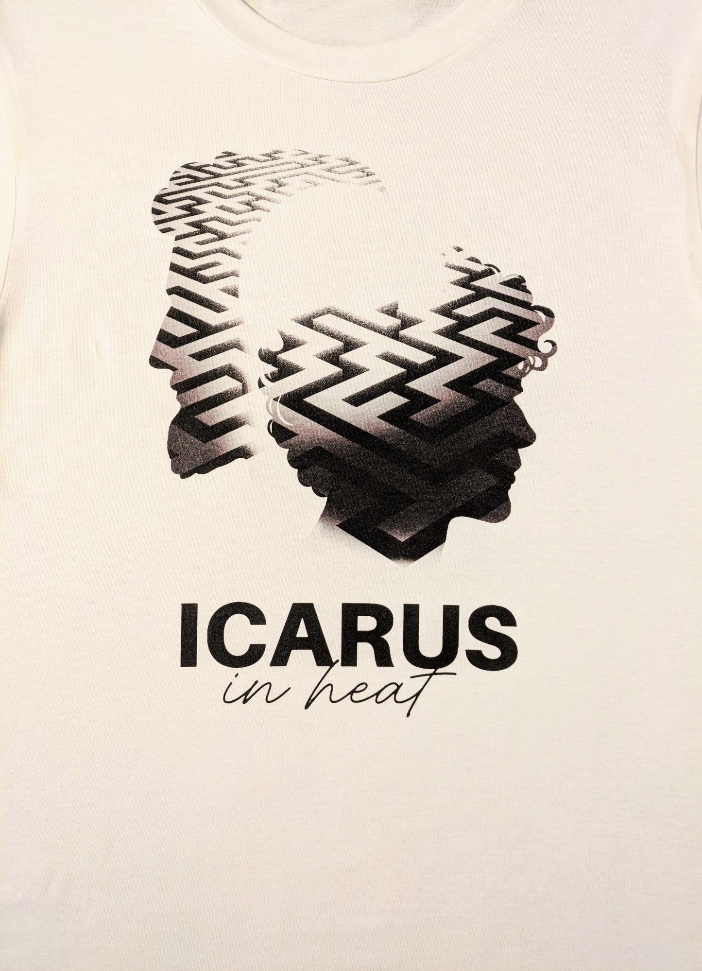 White tee with two male shiloettes one yonger one older with a complex maze inside their shadow, Icarus In Heat in text underneath
