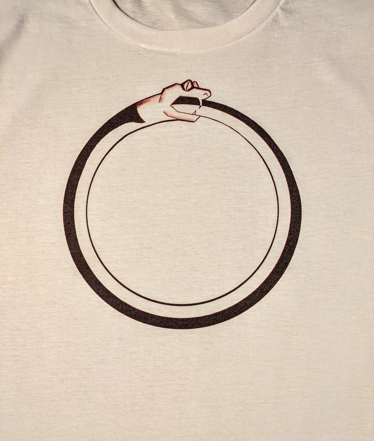 White t-shirt with a black circular design of a snake eating its own tail