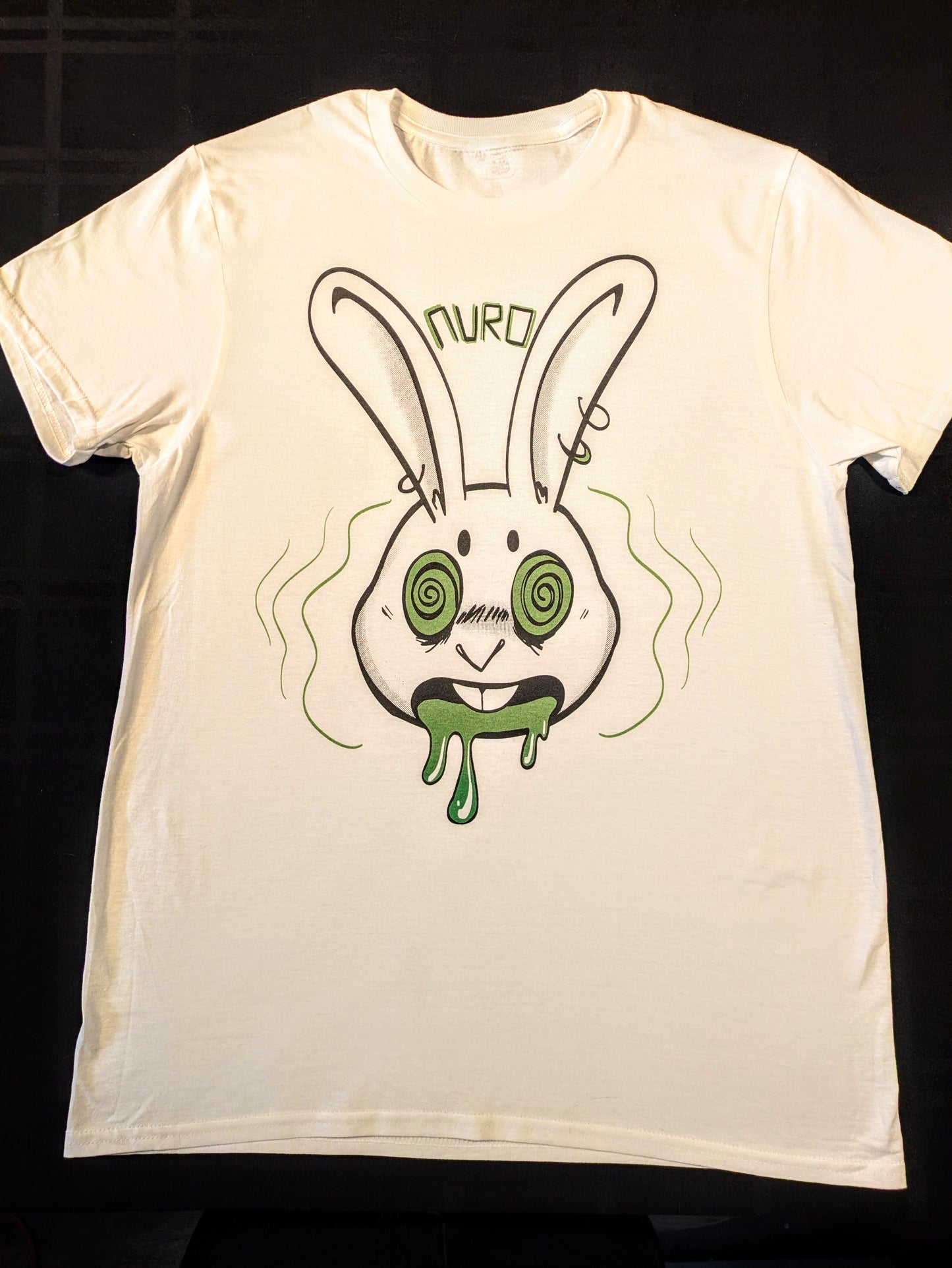 White t-shirt with a pierced anthro rabbit with green hypnotized eyes, open mouth and green drool with block letters between the ears spelling Nuro