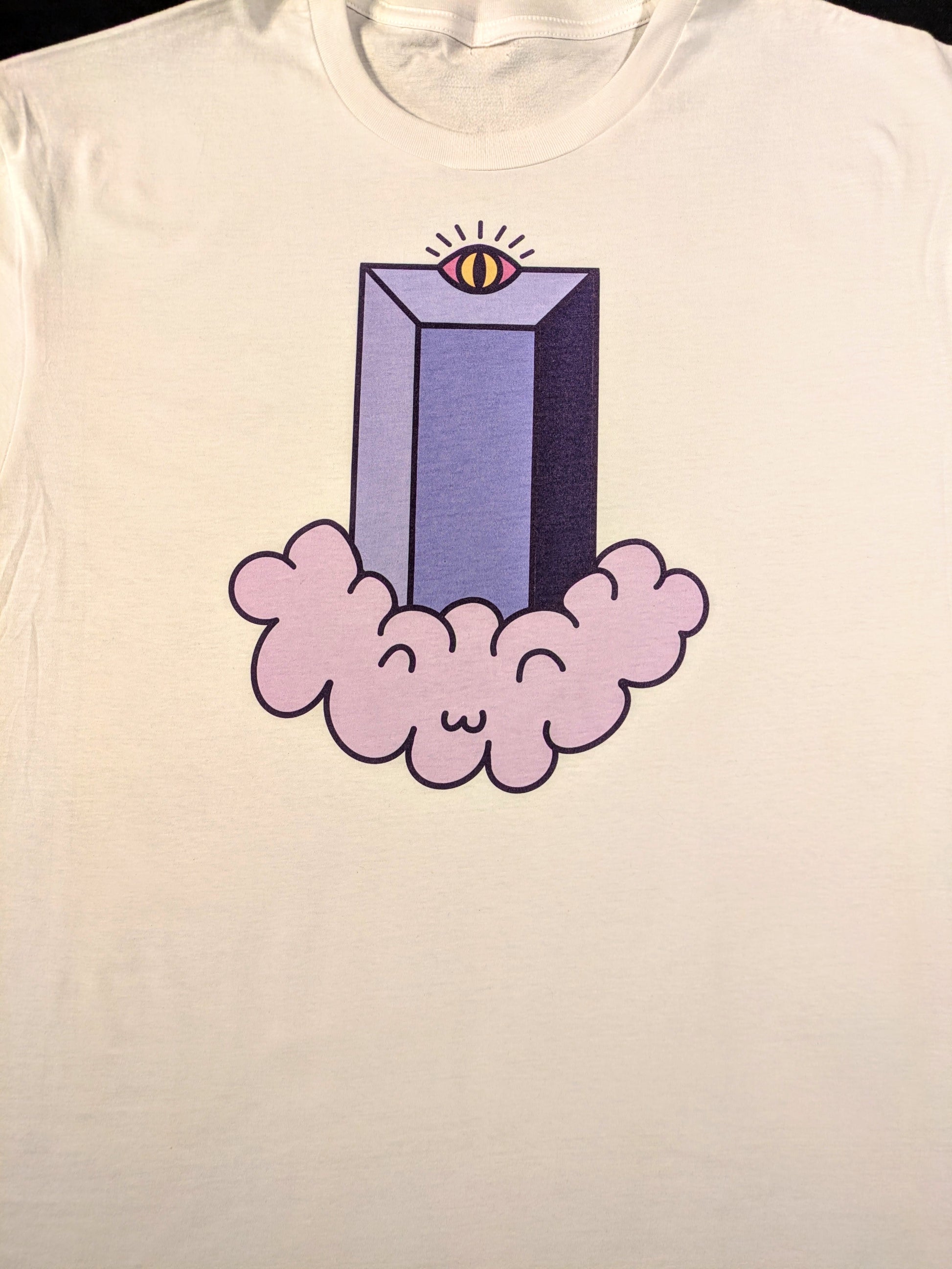 A white tee with a cartoonish version of the Fifth Third Building in Lexington. It has a Radiant eye at the top and is sitting on top of a light purple floating cloud that has a chibi like smiling face